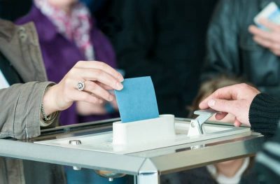 Une main glisse un bulletin de vote dans une urne
